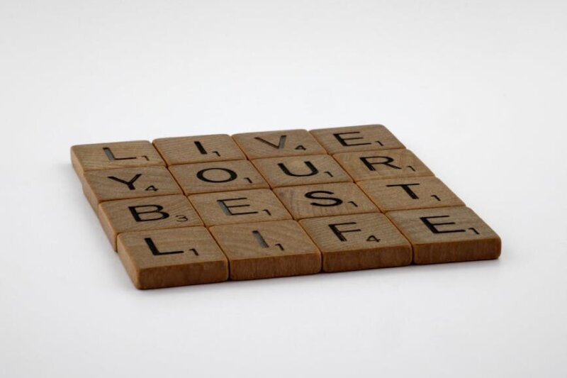 Scrabble tiles spelling 'Live Your Best Life' on a white background.